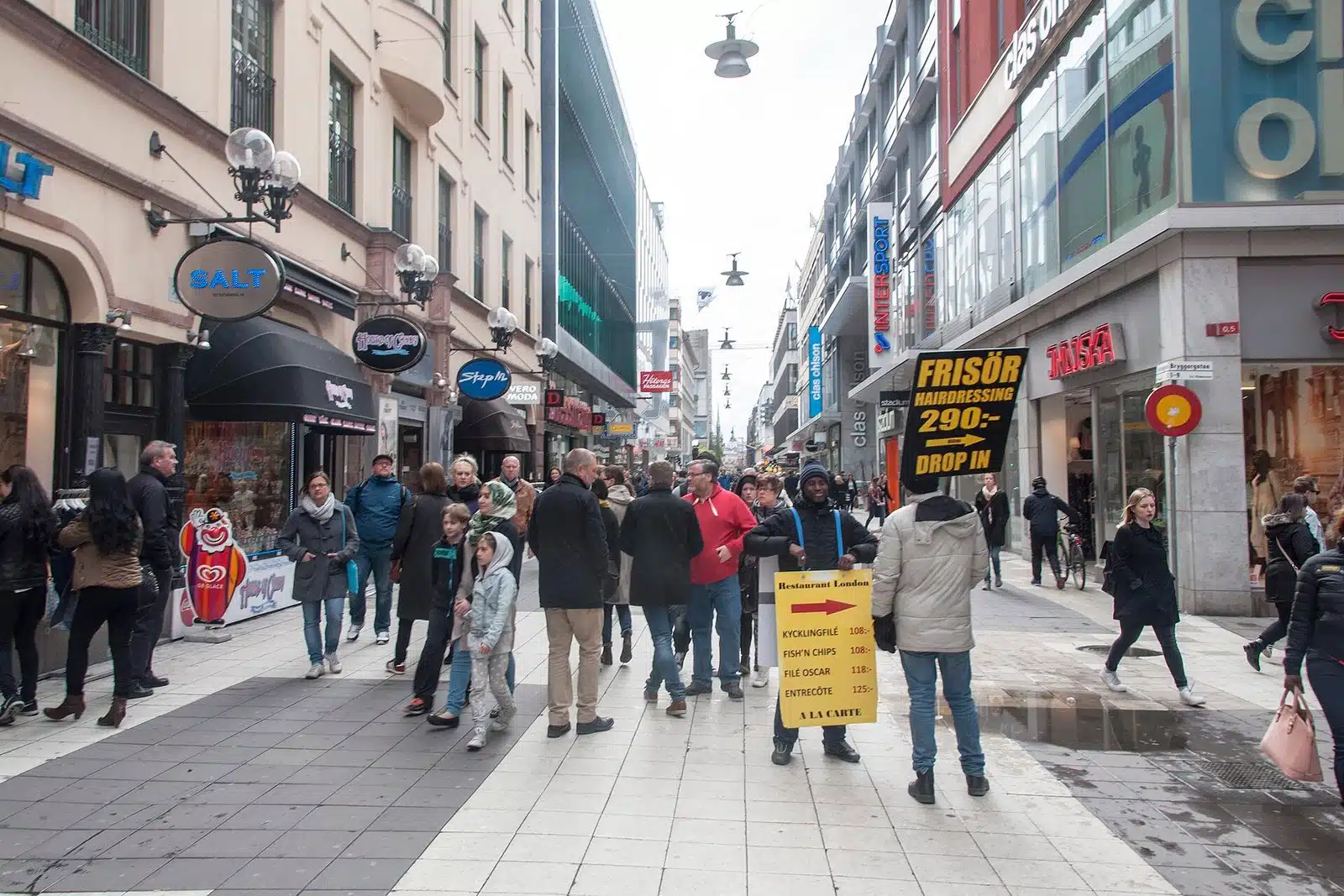 Gågatan Drottninggatan i Stockholm med fotgängare och butiker