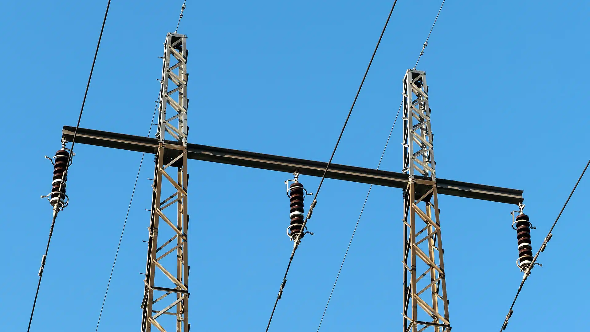 Elmaster med kraftledningar mot himlen