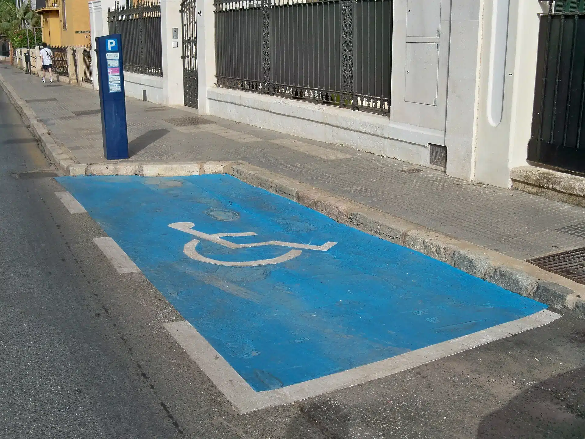 En blåmålad parkeringsplats reserverad för personer med rörelsehinder vid en gata i Málaga
