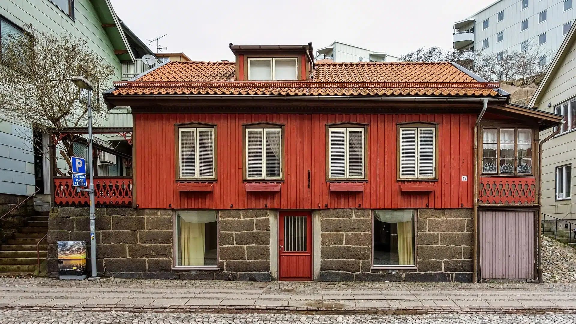 Ett rött trähus med vita knutar i svensk miljö