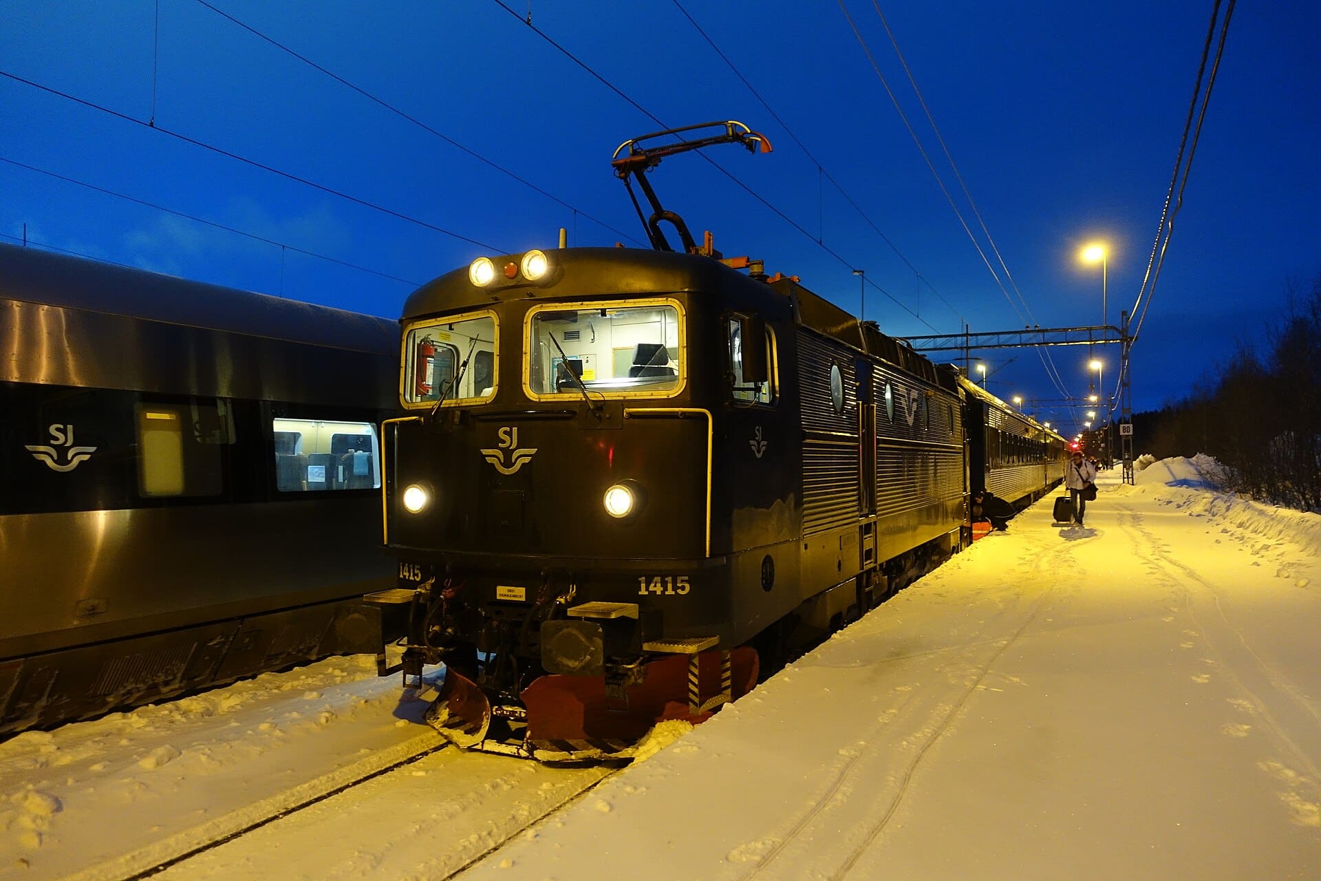 Ett nattåg står vid en snöig perrong i Duved i kvällsmörker